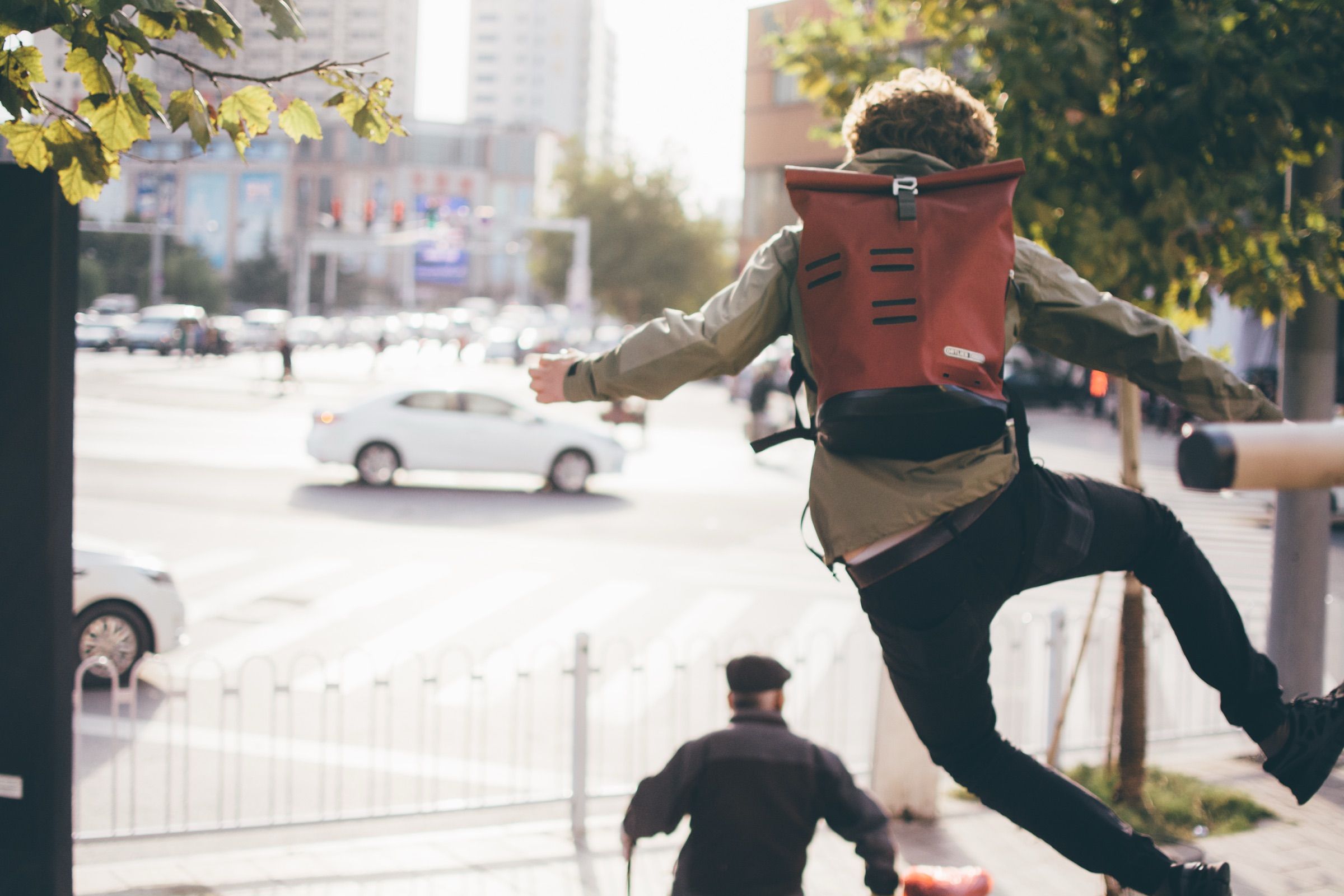 Traveler leaping across a street wearing an Ortlieb backpack