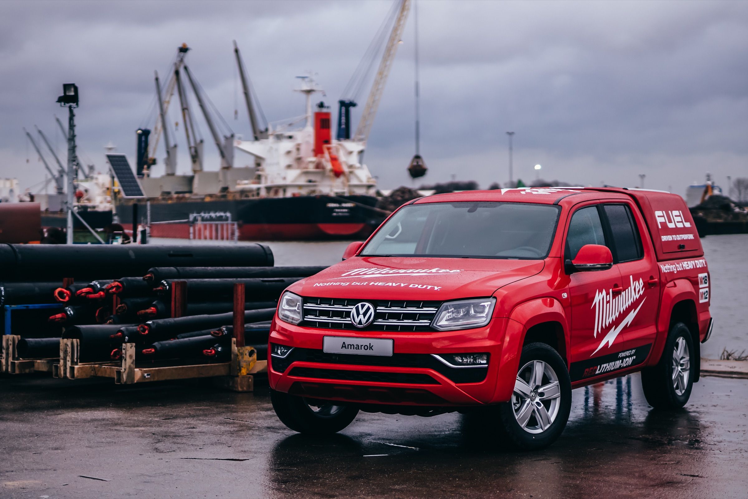 Red VW Amarok pickup with PSB branding in an industrial harbor setting